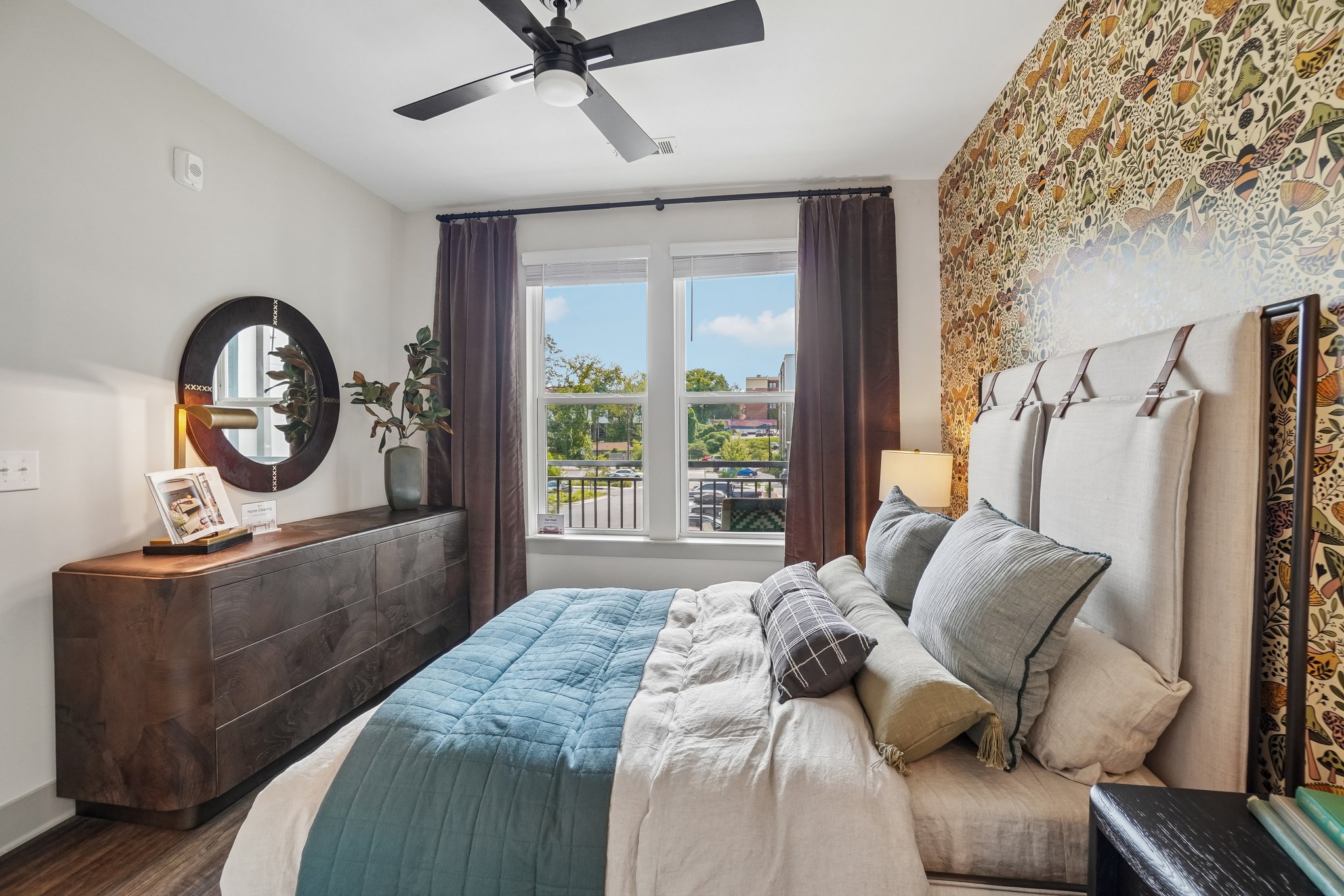 Model bedroom with large window and ceiling fan at The Avery